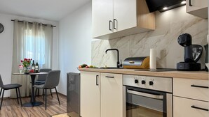 Eine moderne Küche mit Einbauofen, Kaffeemaschine und Essbereich mit Tisch und Stühlen.
