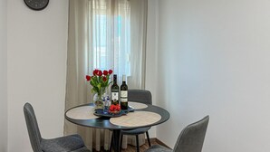 Ein Esstisch mit vier Stühlen, einer Vase mit roten Blumen und zwei Weinflaschen.
