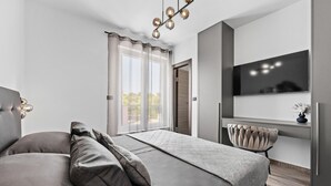 Ein modernes Schlafzimmer mit einem großen Bett, einem an der Wand montierten Fernseher und Blick ins Freie.