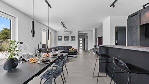 Eine moderne Küche mit einem langen Esstisch, einer Bar und einem eingebauten Ofen.