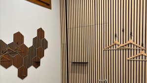 Een kamer met een houten vloer, een schuifdeur met verticale lamellen, een wanddecoratie van houten honingraten en een raam boven de deur.