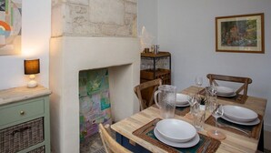 Un coin repas avec une table en bois dressée pour quatre personnes, une cheminée et une carte accrochée au mur.