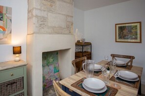 A dining area with a wooden table set for four, a fireplace, and a map on the wall. - Charming Family Cottage in Bath w/Parking (Bath)