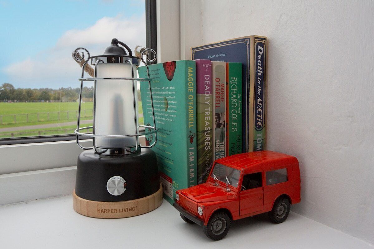 Un alféizar con una hornilla portátil, un coche de juguete rojo y libros.
