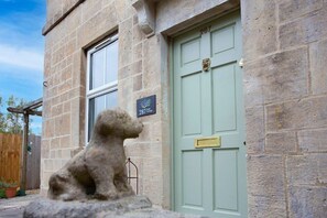 A stone building with a green door, a stone statue of a bear, and a sign reading "287 Cottage". - Charming Family Cottage in Bath w/Parking (Bath)