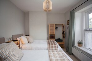 A bedroom with two beds, a wooden wardrobe, a radiator, and a window with curtains. - Charming Family Cottage in Bath w/Parking (Bath)