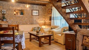 Un accogliente soggiorno con parete in pietra, arredi in legno e una scalinata con elementi decorativi.