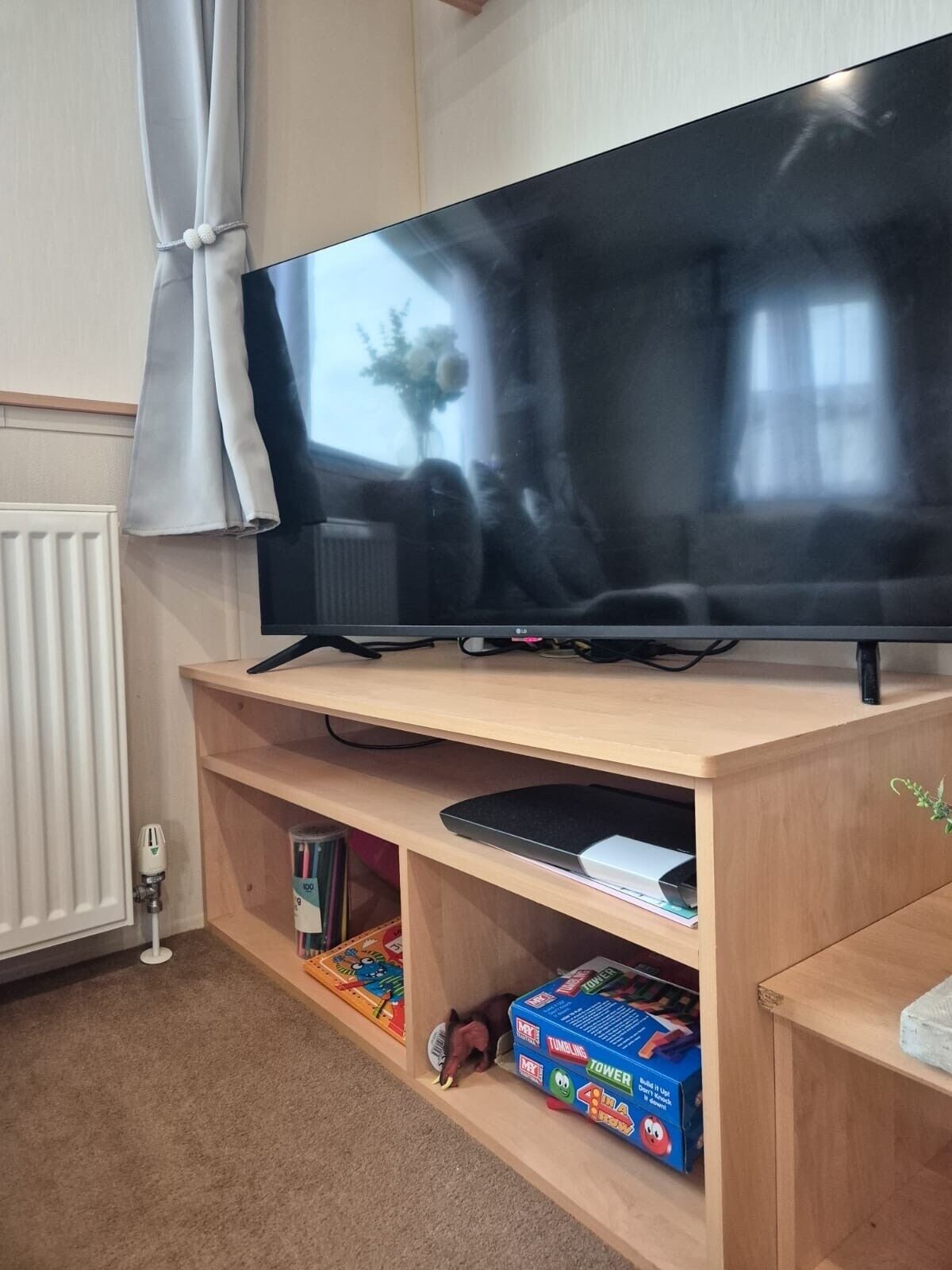 A flat-screen TV on a wooden stand with shelves below.