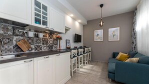 A modern kitchen with white cabinets, a tiled backsplash, and a bar area with stools. - Nice apartment in Silo with WiFi (Silo)