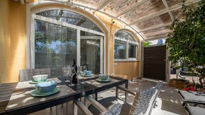 A covered patio with a table set for dining, featuring glassware and a bottle. - Nice apartment in Silo with WiFi (Silo)