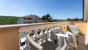 A balcony with a table set for two, overlooking a scenic landscape with buildings and trees. - Gorgeous apartment in Silo with outdoor swimming pool (Silo)