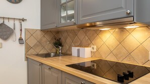 A kitchen with grey cabinets, a stainless steel sink, and a black induction cooktop. - Gorgeous apartment in Silo with outdoor swimming pool (Silo)