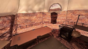 A tent interior with a sleeping area, a small window, and a table with a bag.