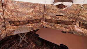 A tent with a sleeping area, a small table, and a bench.