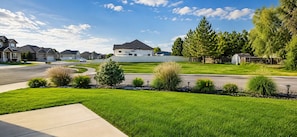 A suburban neighborhood with single-family homes, a well-maintained lawn, and a clear sky.