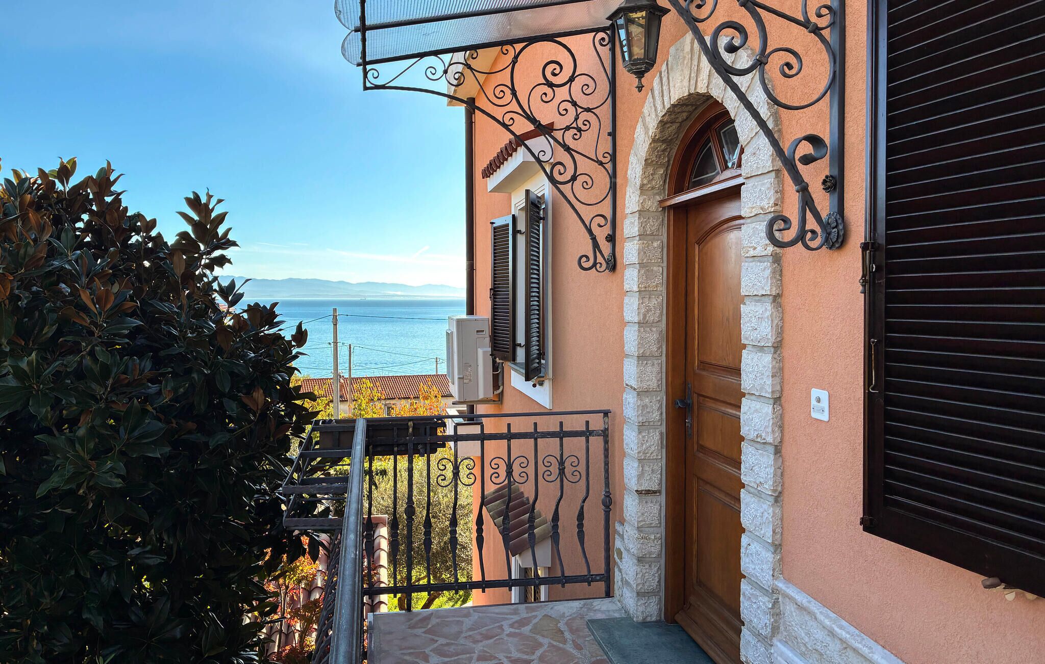 Un bâtiment situé sur la côte, doté d’un escalier en pierre, d’une porte en bois et offrant une vue sur la mer.