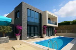 A modern two-story house with a swimming pool, large windows, and potted plants. - VibaVilla Elite – Private Luxury Villa with Pool and Sea View (kusadasi)