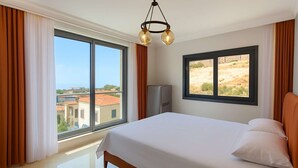 Quarto de hotel com uma cama grande, vista da cidade e um lustre moderno.