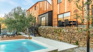 Uma casa moderna de madeira com piscina, área de estar ao ar livre e parede de pedra.