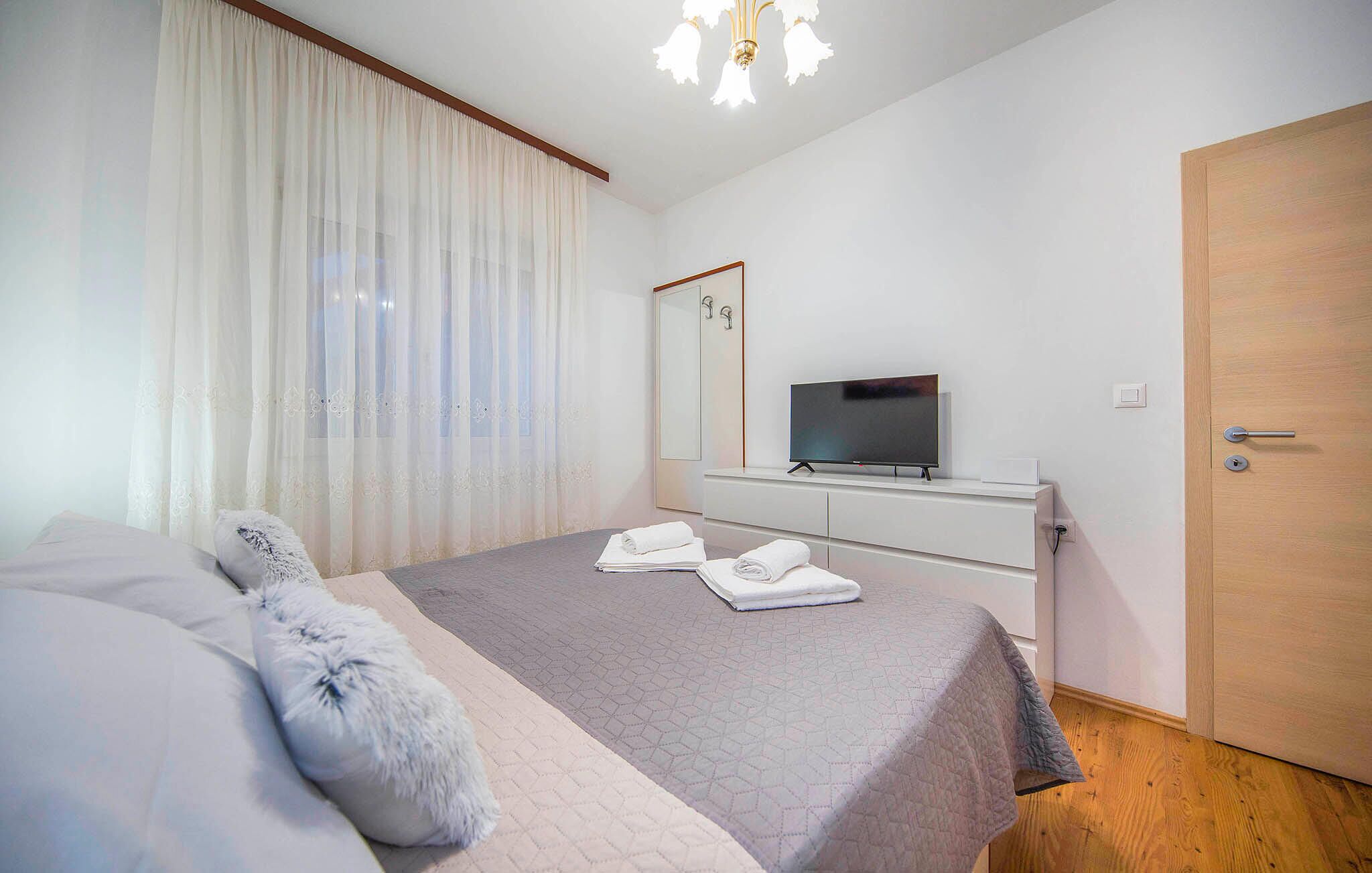 Een moderne hotelkamer met een bed, een televisie, een dressoir en een deur.