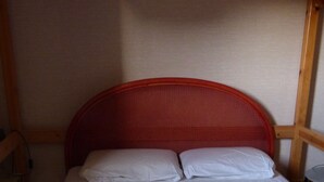 Een eenpersoonsbed met een rode hoofdbord en wit beddengoed in een kamer met houten wanden en een houten vloer.
