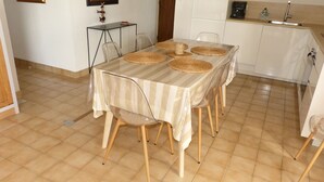 Een eethoek met een tafel bedekt met een streepjes tafelkleed, omringd door stoelen met houten poten.