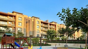 A playground with swings, slides, and a climbing structure, surrounded by a well-maintained lawn and a paved area. - spacious apartment w/ pool and garden view (Cairo Governorate)
