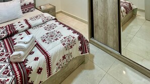 A modern bedroom with a large bed, a nightstand, a wooden wardrobe, and a mirror. - spacious apartment w/ pool and garden view (Cairo Governorate)