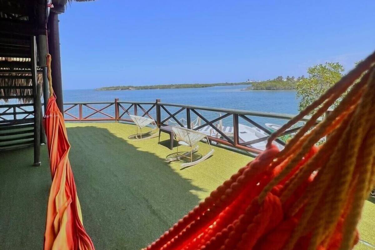 Un hamac sur une terrasse, avec vue sur la mer et une île lointaine.