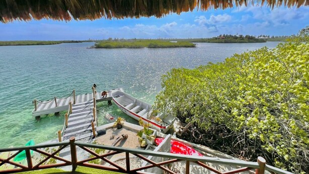 A dock with a boat, clear water, and a view of a distant island. - El Arca (Isla Tintipán)
