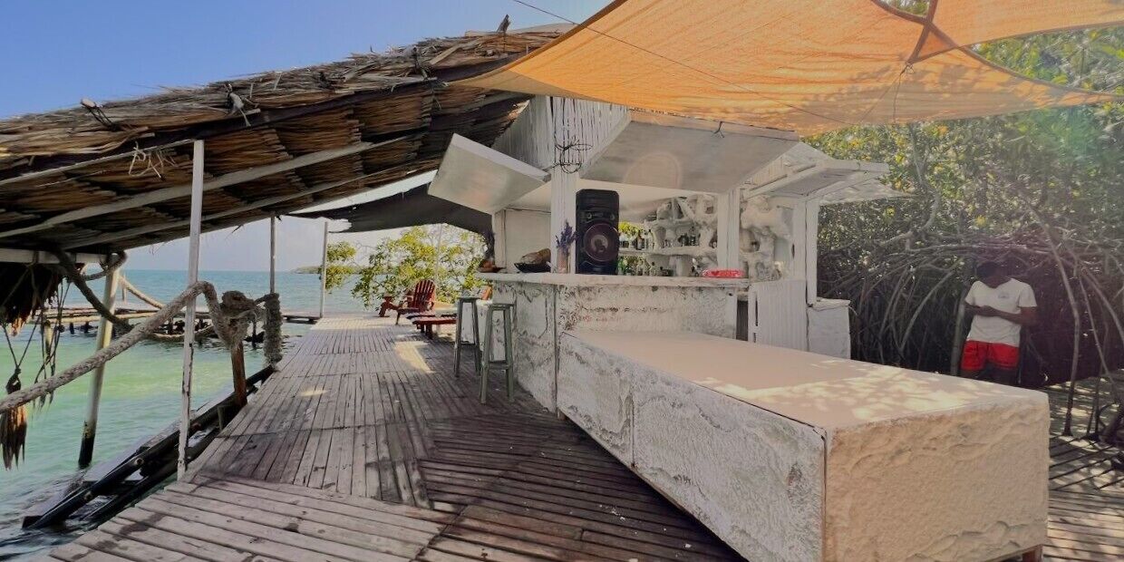 A wooden deck with a concrete bar area, a thatched roof, and a view of the sea.