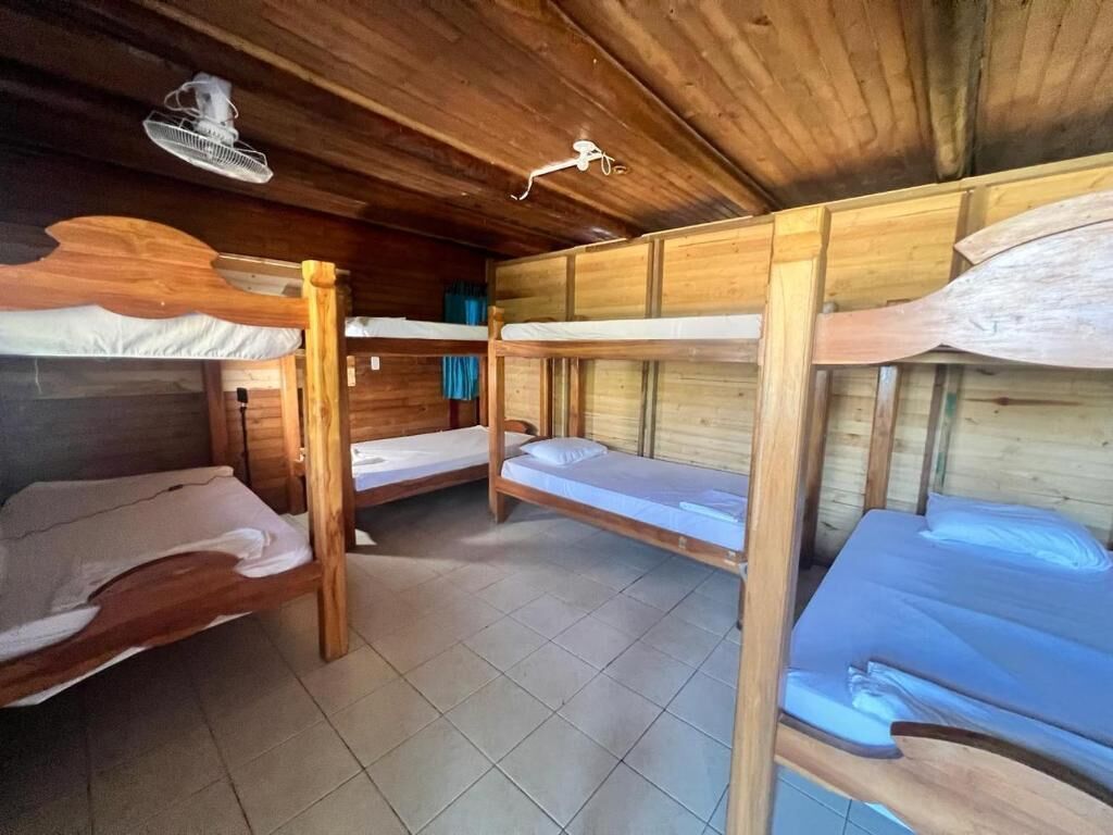 A cabin with wooden bunk beds, a fan, and a window with curtains.