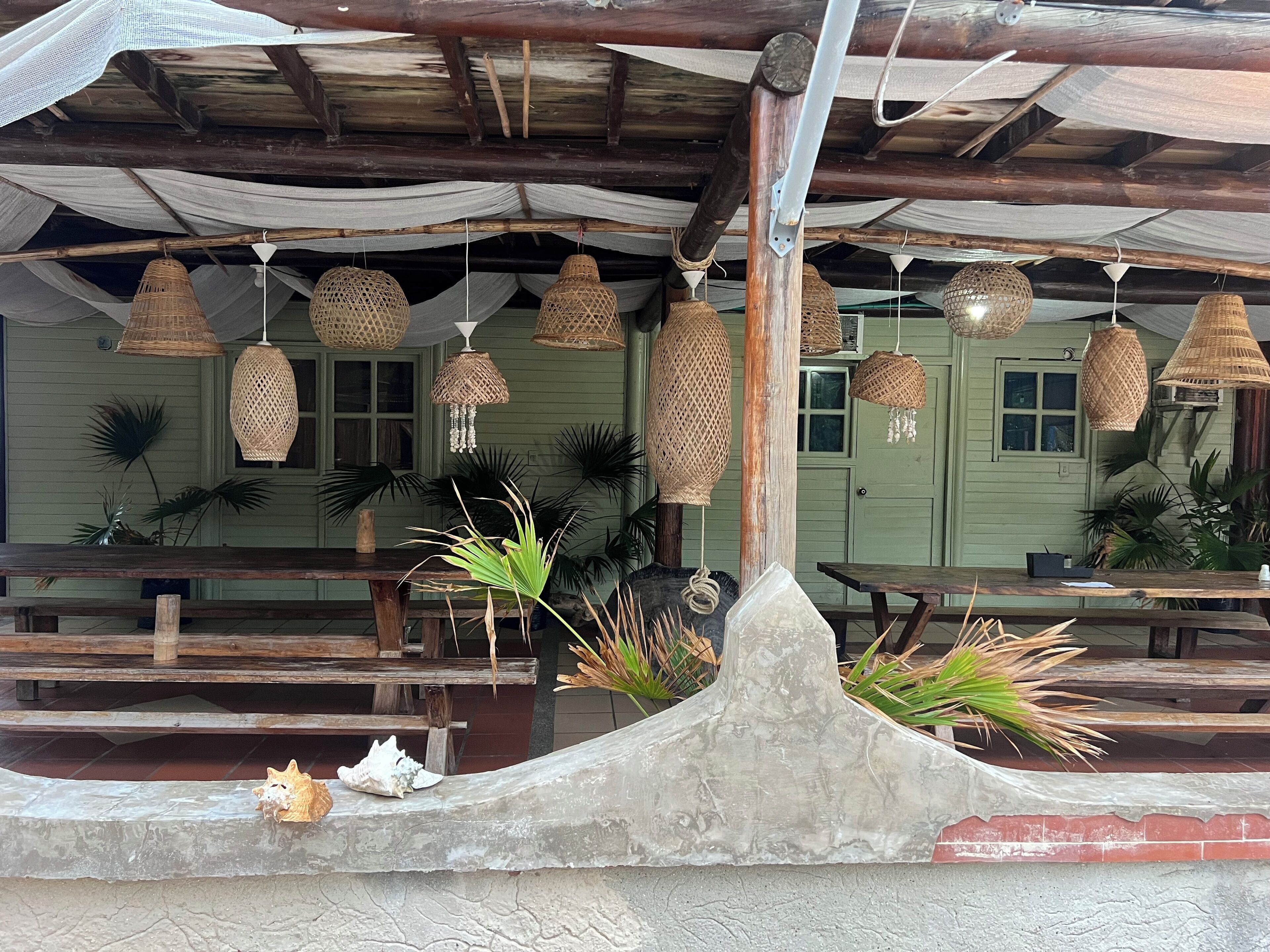 A rustic outdoor seating area with wooden benches and woven hanging lights.