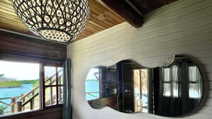 A room with a large window, a wooden ceiling, and a unique wall-mounted mirror. - El Arca (Isla Tintipán)