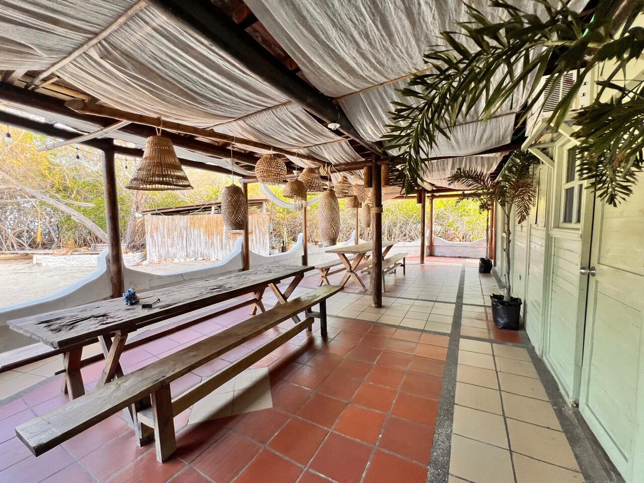 An outdoor covered patio with wooden benches and hanging lanterns.