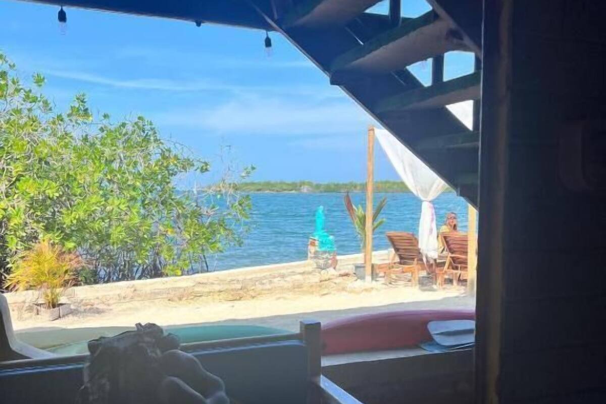 Une vue sur la plage depuis un espace extérieur abrité, équipé d’un banc et d’une table.