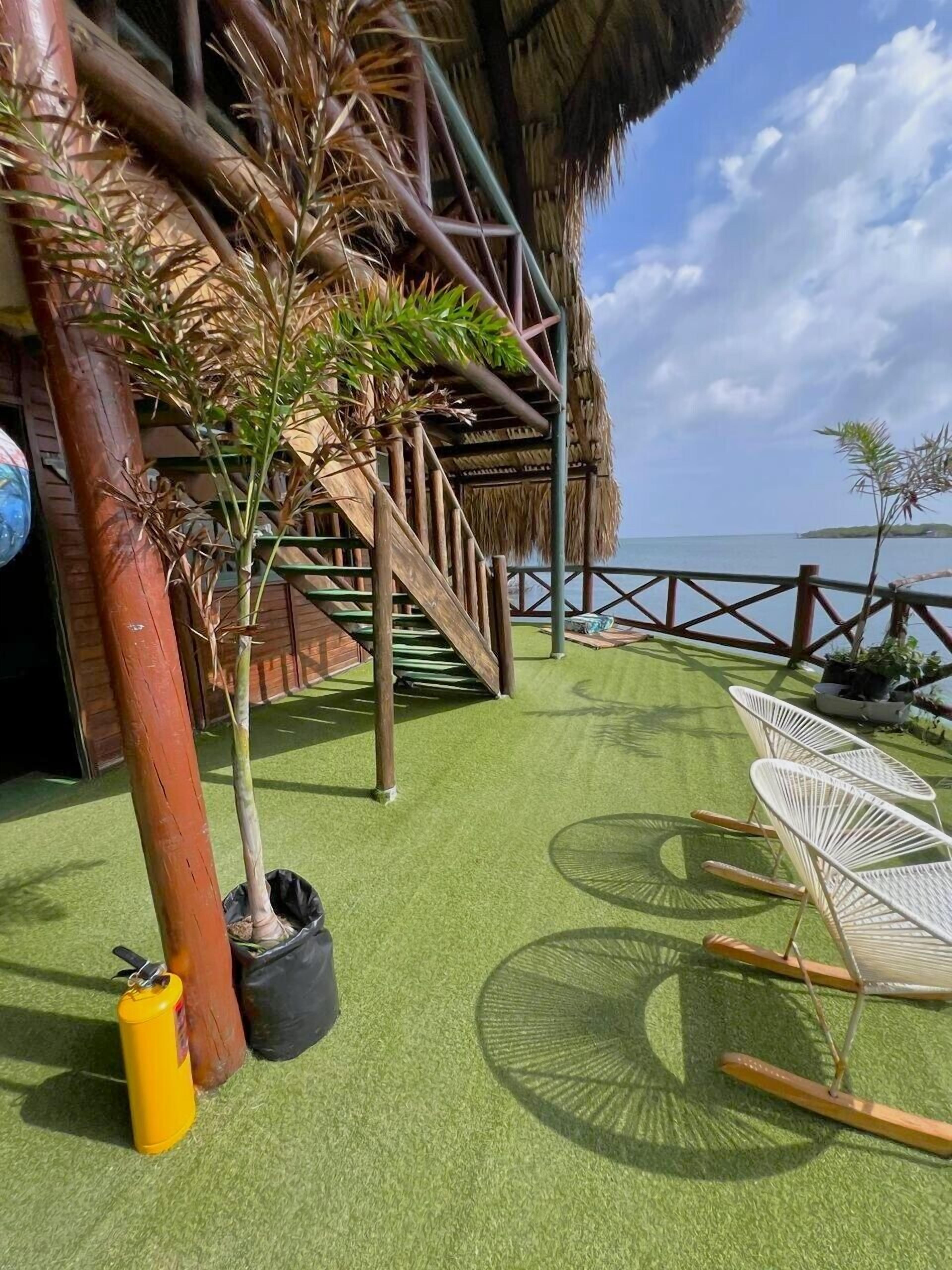 A thatched-roof structure with a staircase, potted plants, and outdoor seating.