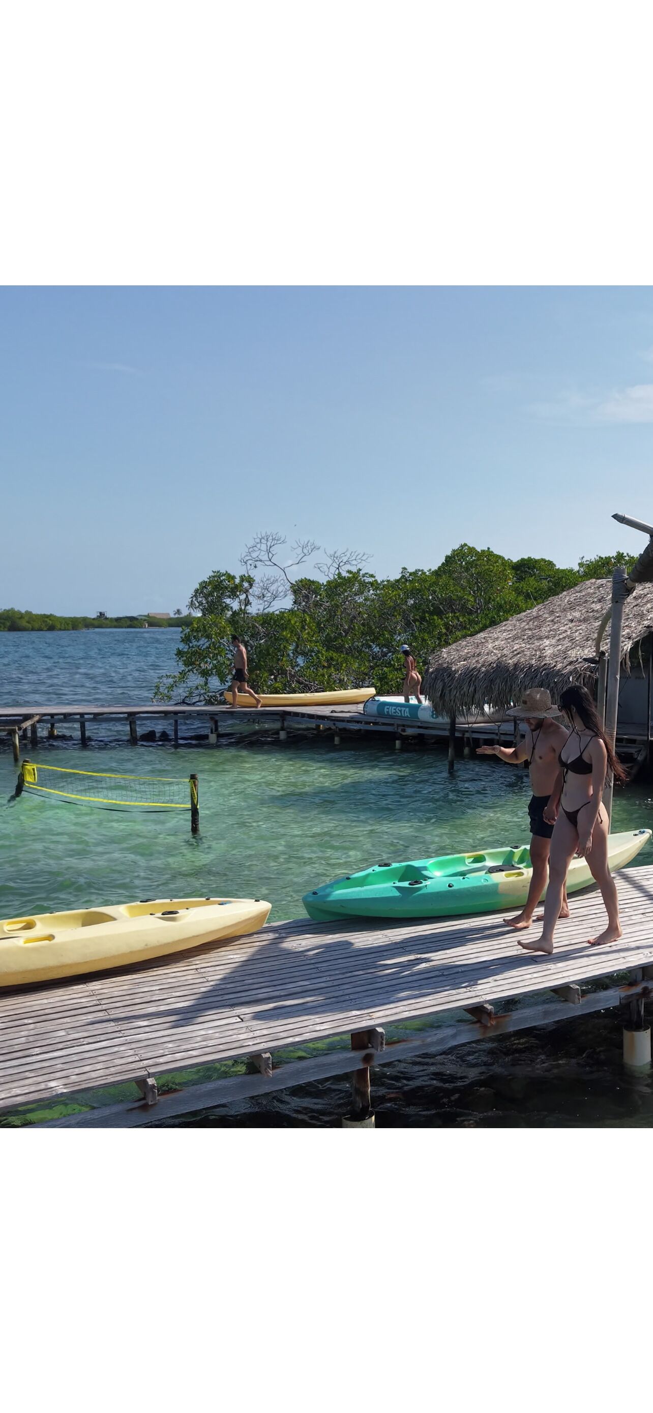 A wooden dock with kayaks and a thatched-roof structure.