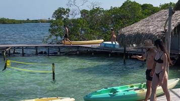 A wooden dock with kayaks and a thatched-roof structure.