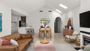 A modern living room with a brown leather sofa, a wooden dining table, and a pink ottoman. - Bayleaf Terrace - A stylish period home in Hawthorn, steps from Glenferrie Road (Hawthorn)