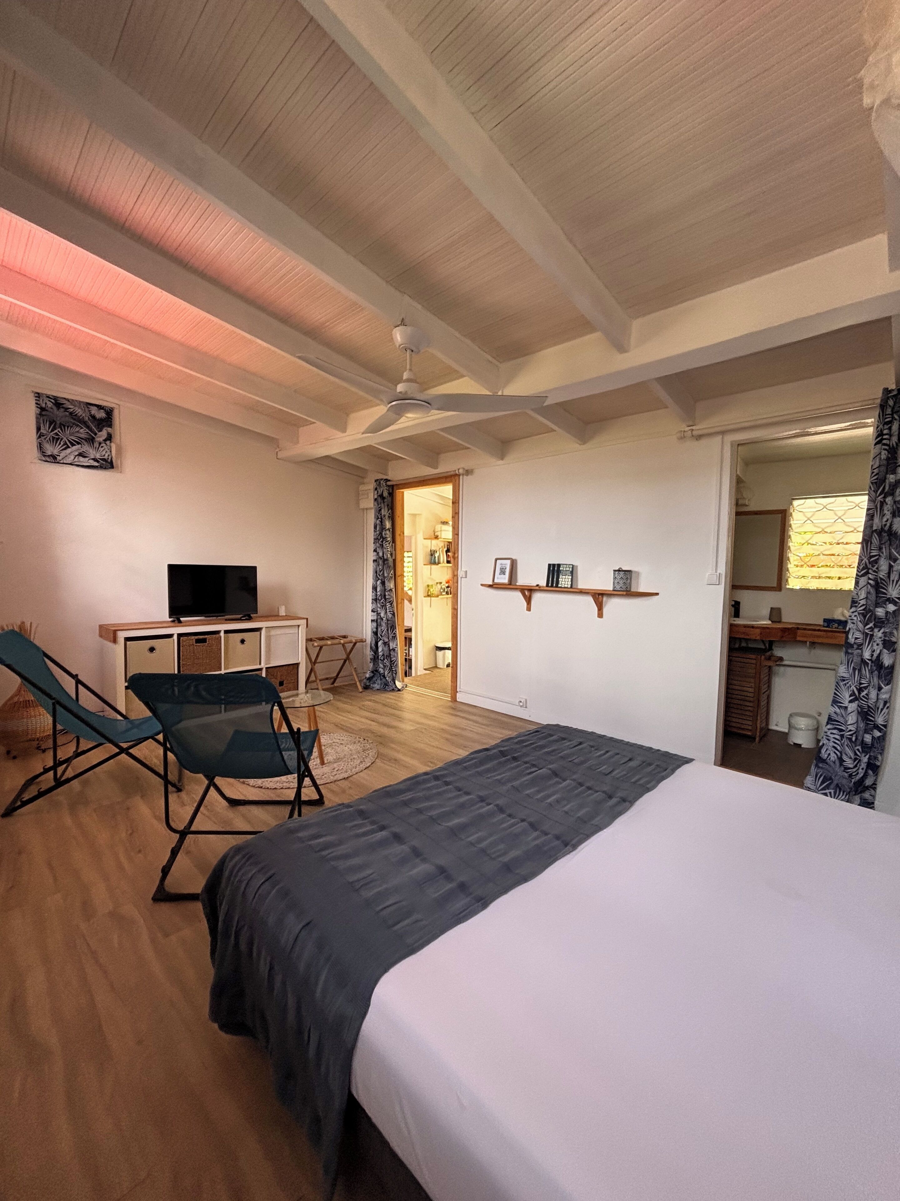 A bedroom with a bed, a TV, a desk, and a chair.