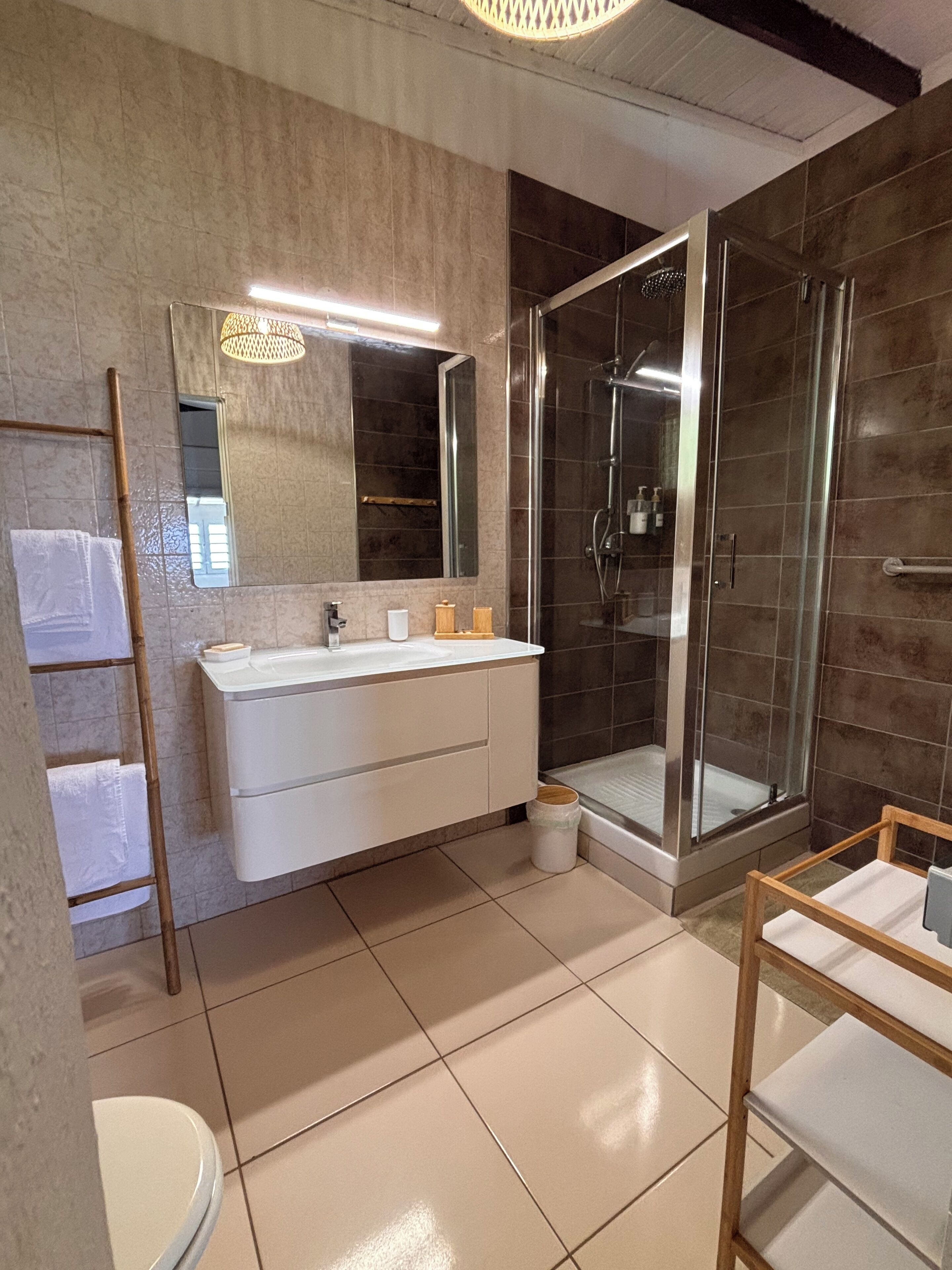 Een moderne badkamer met een grote spiegel, een wastafel met een wasbak, een douchecabine en een toilet.