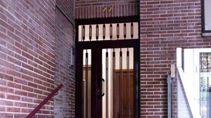 A staircase leading to a door with a metal gate, surrounded by brick walls and a glass railing. - Spacious, modern, and central 2-bedroom apartment with 1 bathroom in Madrid (Madrid)