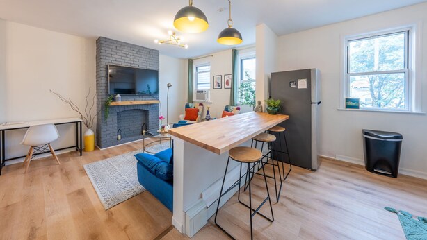 Una cucina moderna con isola centrale, sgabelli da bar, forno integrato e illuminazione a sospensione.