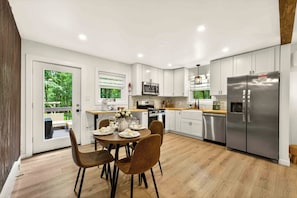 A modern kitchen with white cabinets, stainless steel appliances, and a dining area with a table set for four.