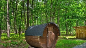 Une structure cylindrique en bois, dotée d’une porte, et entourée d’une forêt.