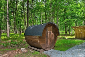 A wooden cylindrical structure with a door, surrounded by a forest.