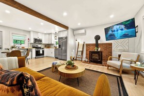A modern living room with a sofa, a coffee table, a fireplace, and a TV mounted on the wall.