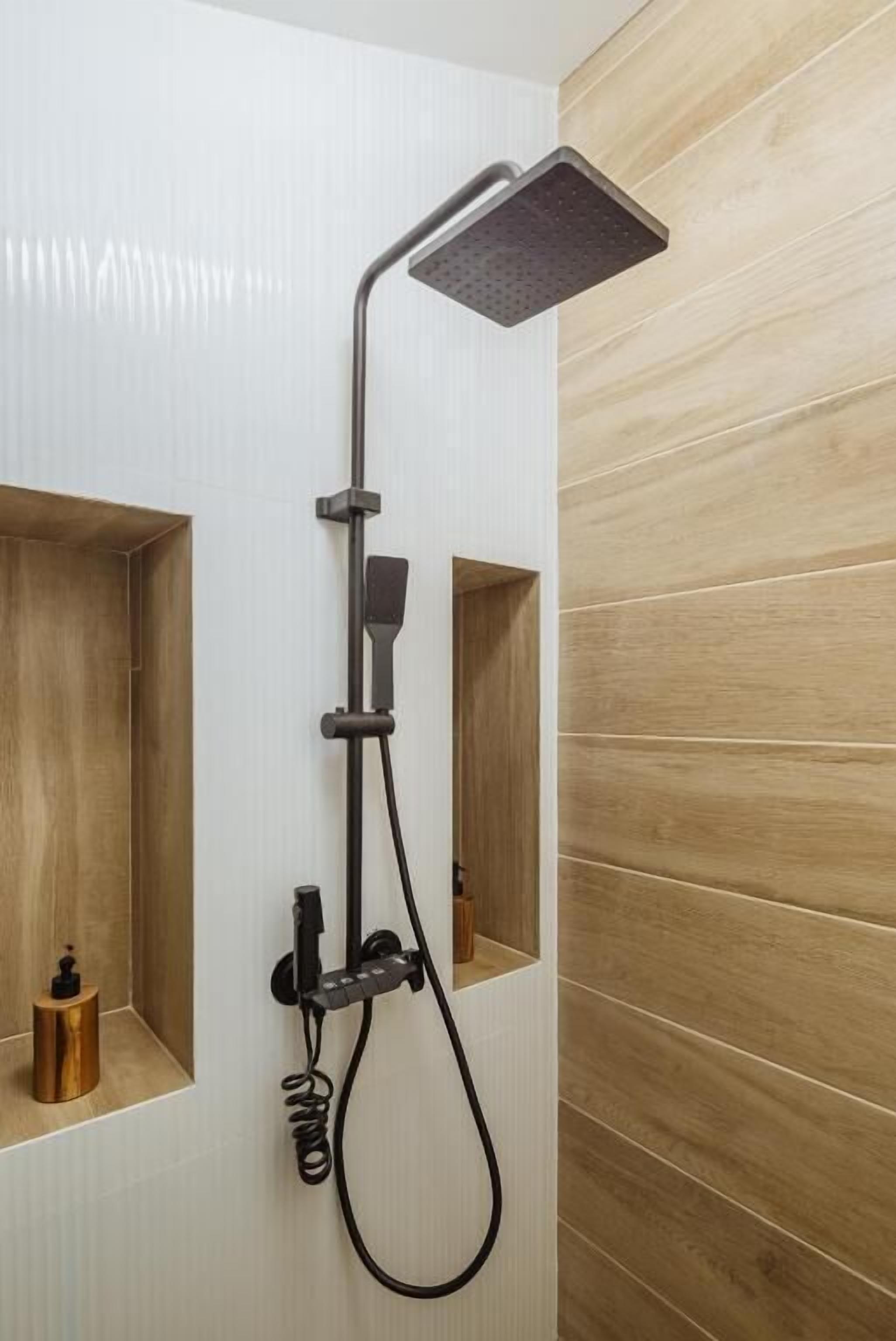A shower with a handheld head, a wall-mounted control panel, and a flexible hose.