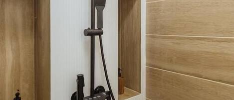 A shower with a handheld head, a wall-mounted control panel, and a flexible hose.